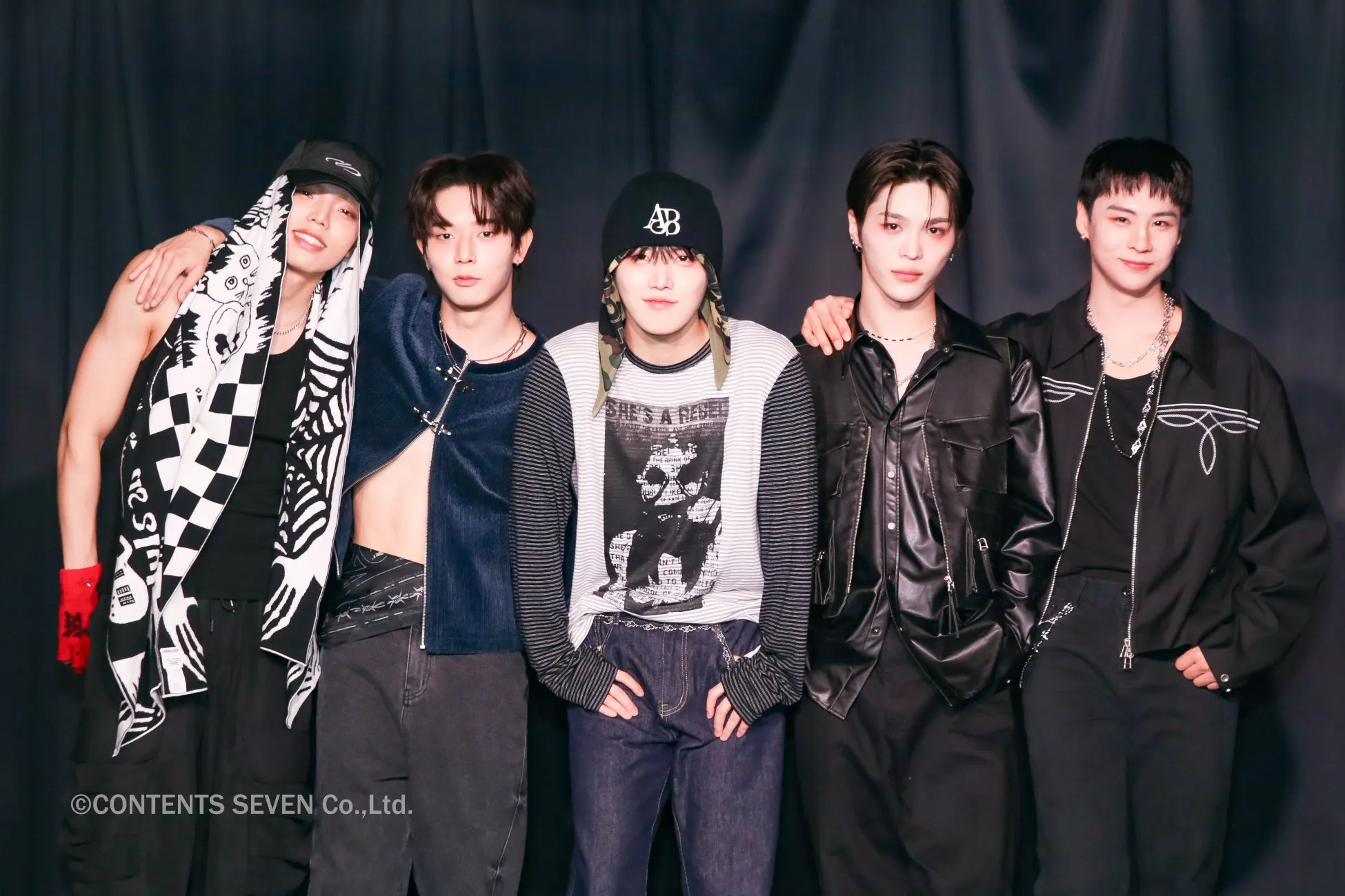 5人の男性グループのポートレート。彼らは様々なファッションスタイルを身につけており、背景は黒。