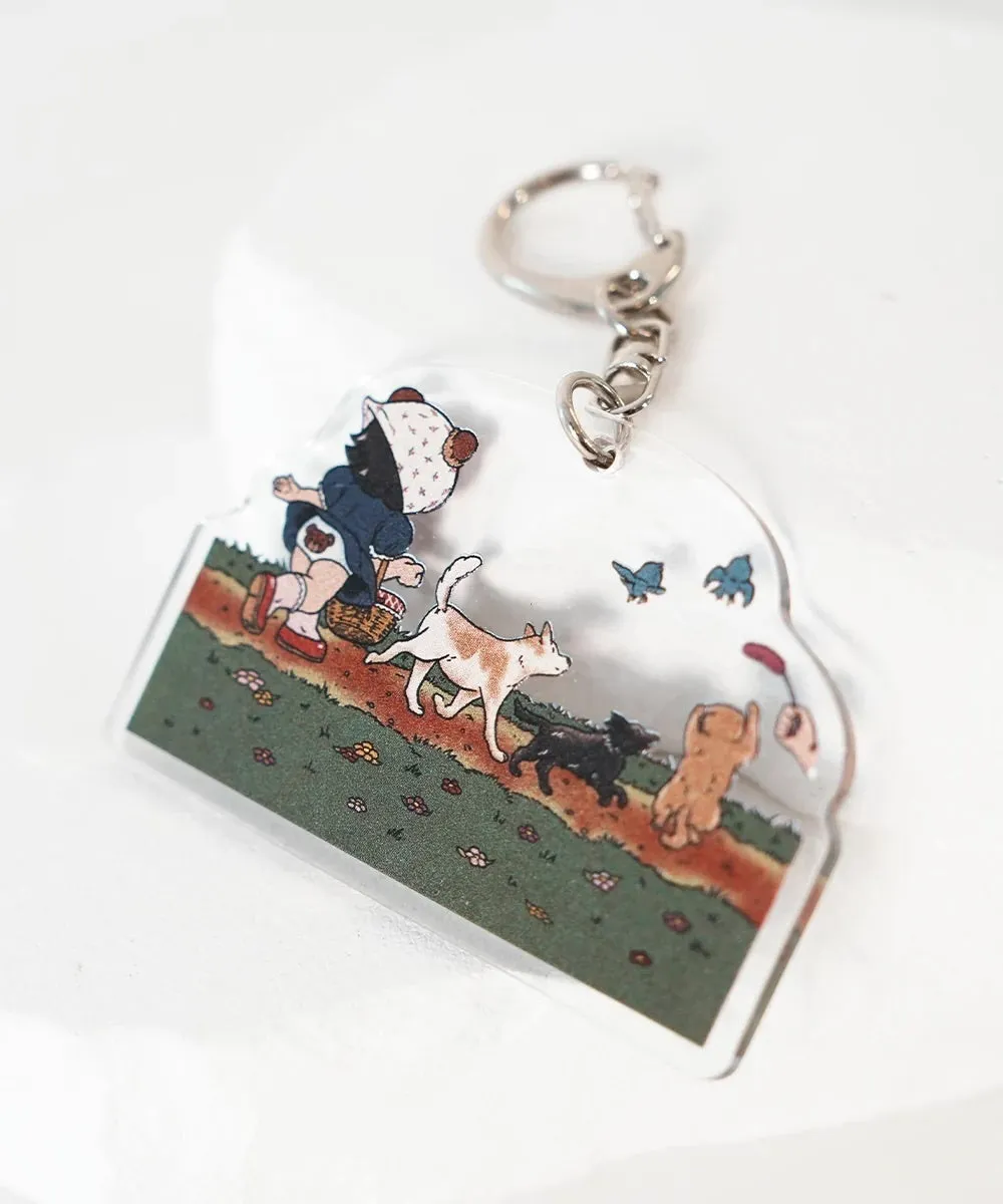 犬と子供のイラストが描かれたキーホルダー。子供が犬と一緒に歩いている様子が描かれています。