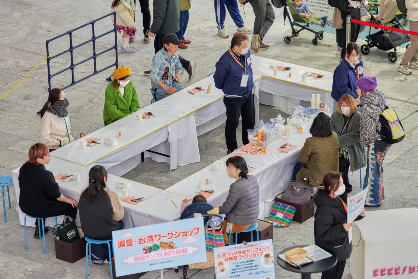 台湾のグルメ食品サンプル制作ワークショップの様子を写した写真です。参加者はテーブルを囲み、マスクを着用して作業しています。ワークショップは、偏愛・台湾ワークショップというテーマで開催されており、食品サンプル制作体験を提供しています。
