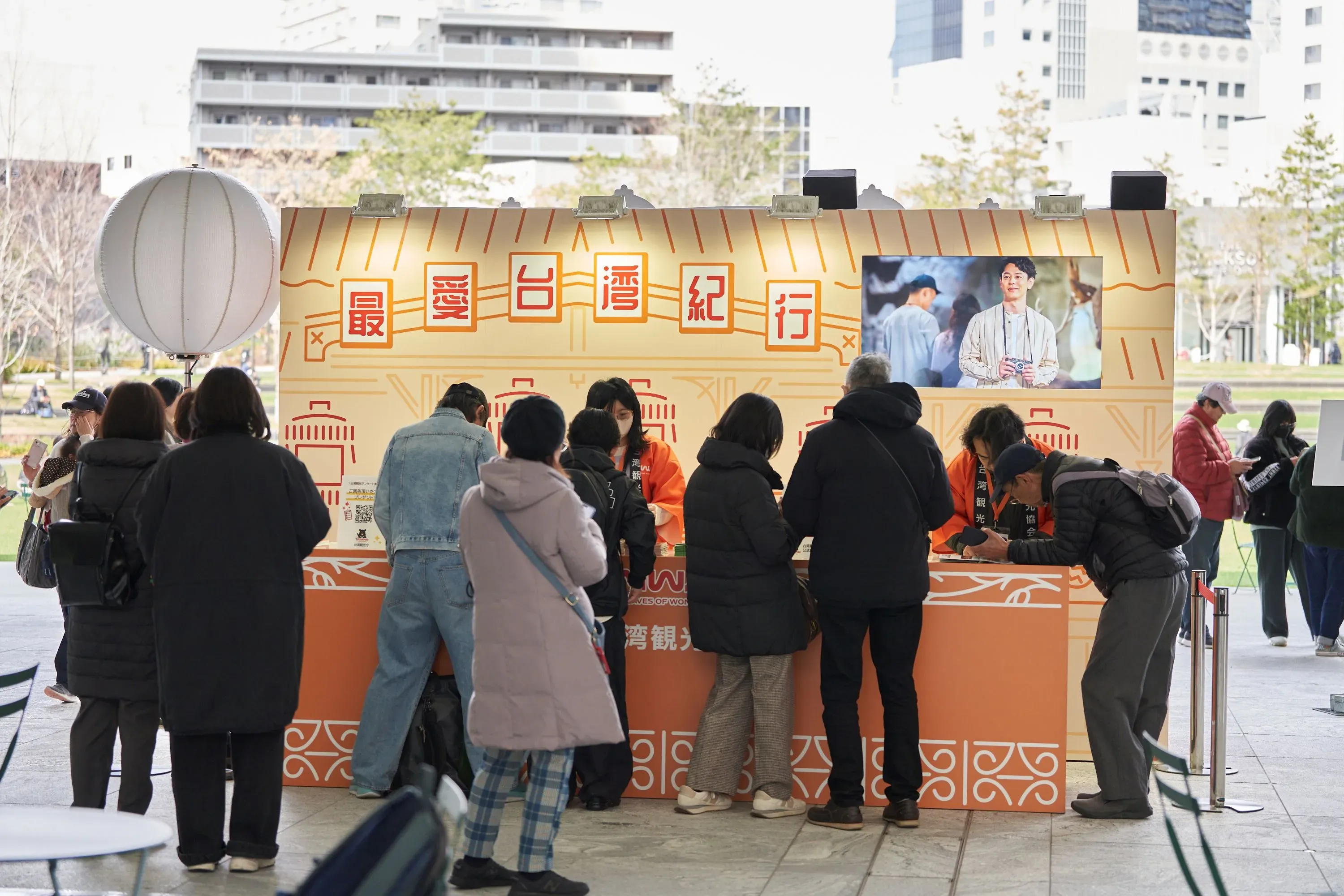 イベント会場の様子。台湾観光をテーマにしたイベントで、多くの人が集まり、案内所のような場所で手続きをしている様子が写っている。看板には「最愛台湾紀行」の文字が見える。
