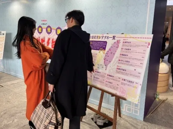 二人の人物が台湾夜市の情報が書かれた看板を見ている様子。