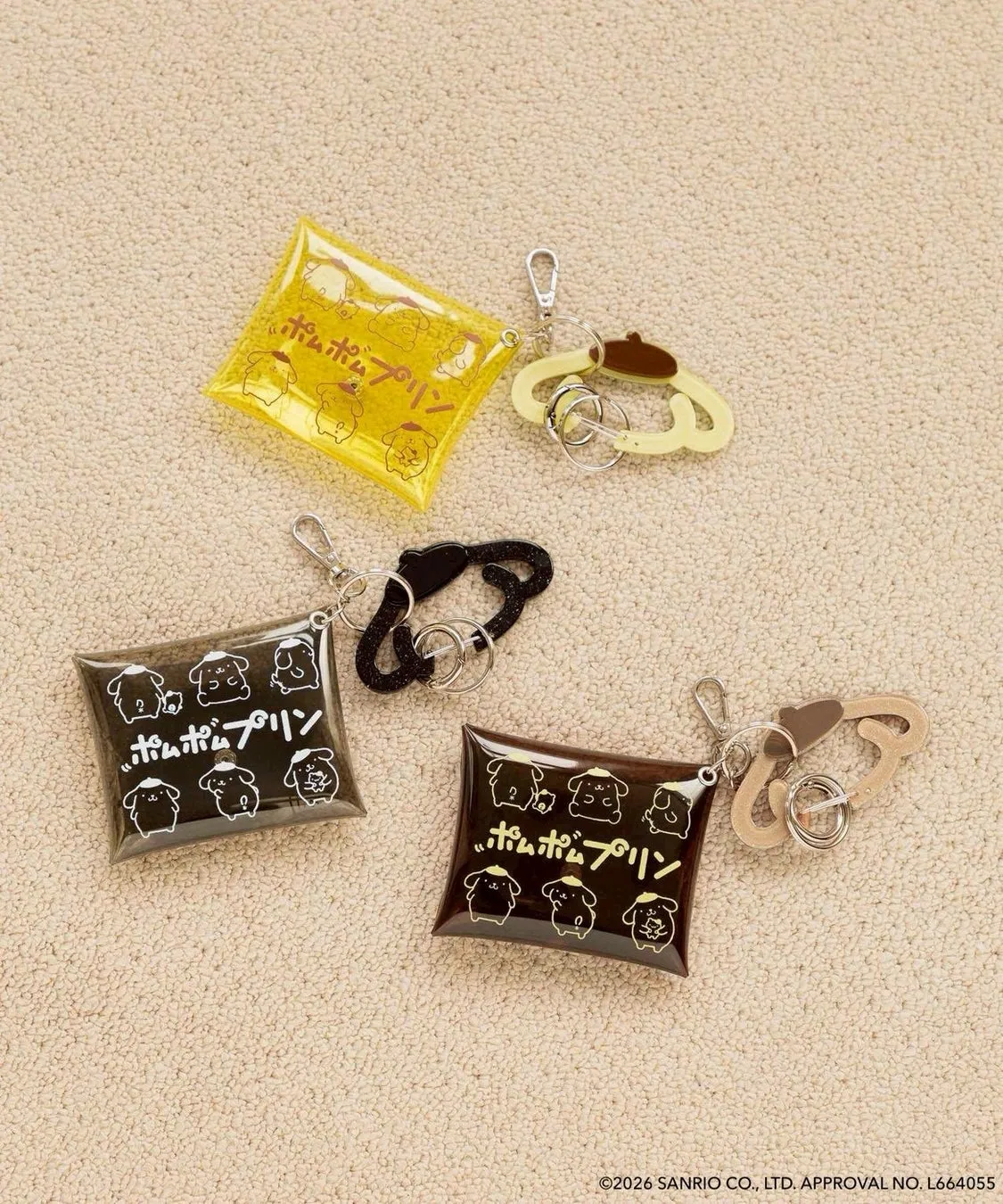 ポムポムプリンのキャラクターグッズの写真です。黄色、黒、茶色の3色のキーホルダーが写っています。