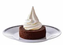 チョコレートケーキの上にソフトクリームが乗ったデザートの画像。