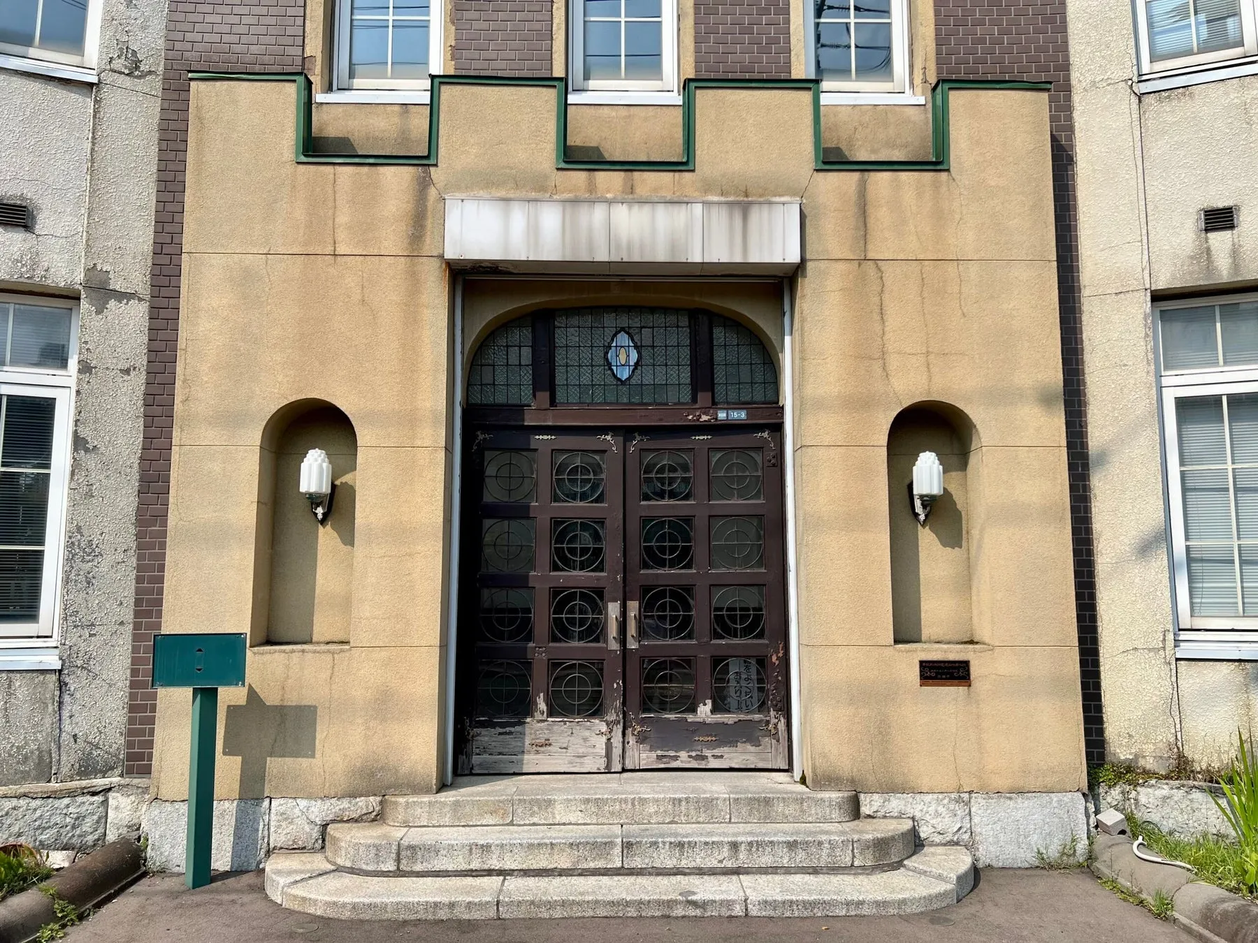 正面玄関の画像です。茶色の木製のドアがあり、円形の窓がいくつかあります。