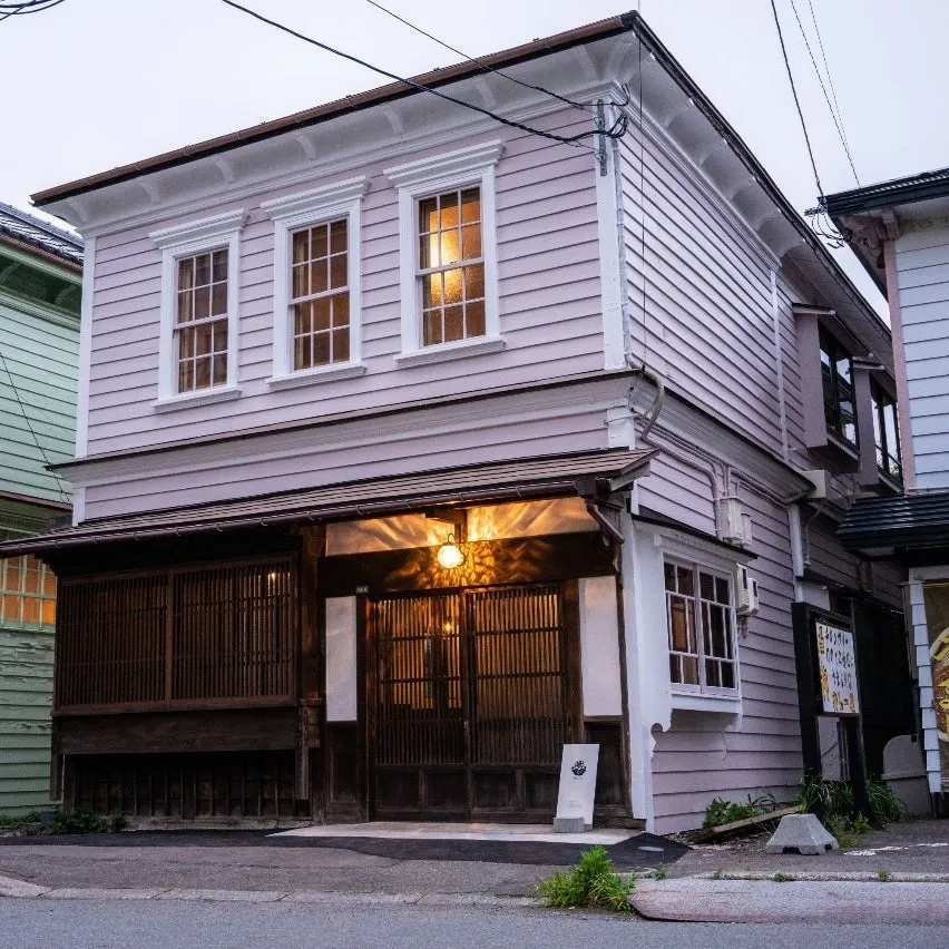 ピンク色の壁と白い窓枠が特徴的な、日本の伝統的な建築様式の建物。