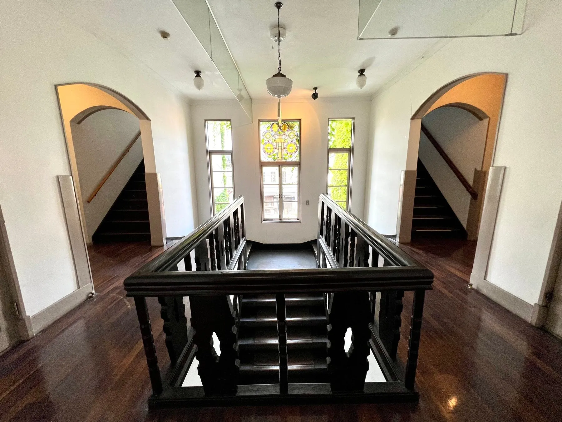 レトロな雰囲気の階段がある内観の写真。左右に階段があり、真ん中にステンドグラスの窓が見える。