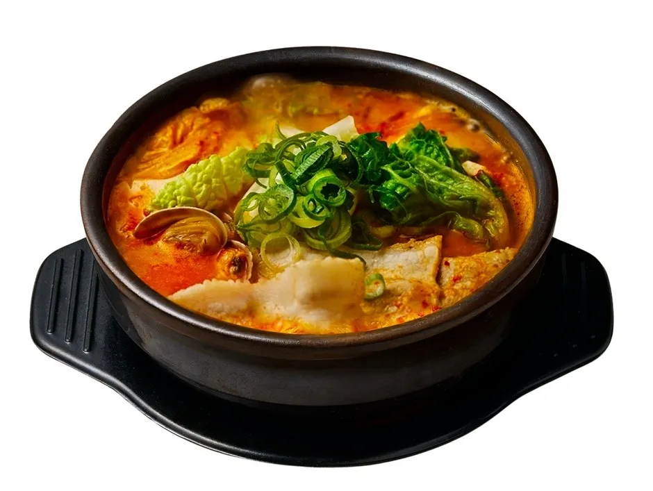 熱々のスンドゥブチゲが黒い器に入った写真。ネギや白菜などの具材がたっぷり。