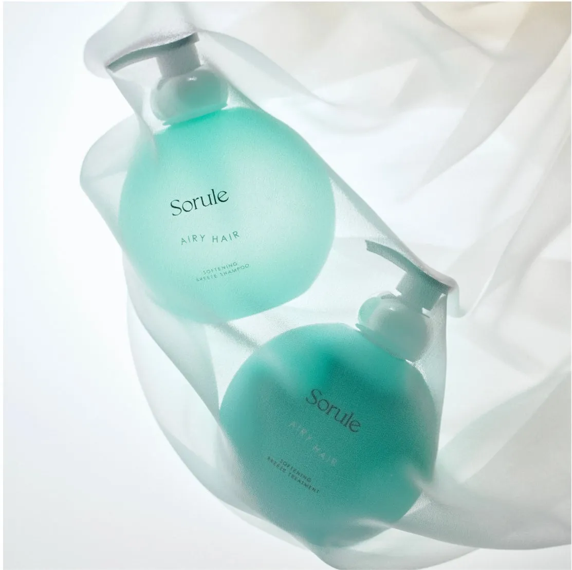 2つの丸いボトルに入ったシャンプーとトリートメントの製品写真。ボトルは水色で、Soruleのブランド名とAiry Hairの文字が書かれている。背景は白い布で、製品が優しく包まれている。