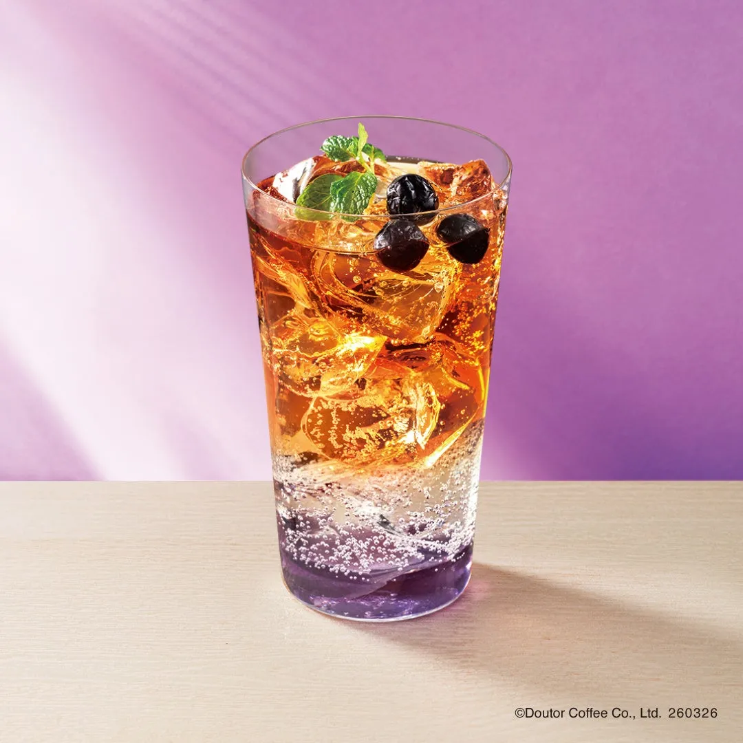 グラスに入ったドリンク。紫色の液体と透明な液体が層になっていて、氷、実、ミントがトッピングされている。