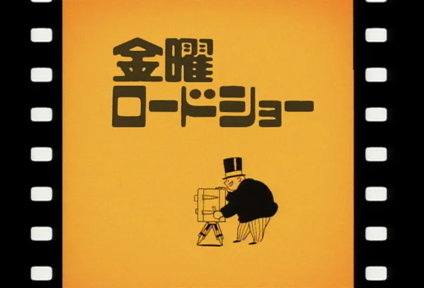 映画のタイトルロゴ。背景はオレンジ色で、黒い文字で「金曜ロードショー」と書かれています。下にはカメラマンのイラストがあります。