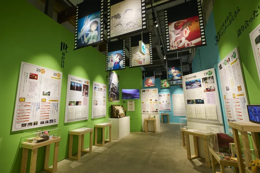 ジブリ作品の展示会の様子。映画のシーンが描かれたフィルム風の展示物や、年表、展示物が並んでいる。