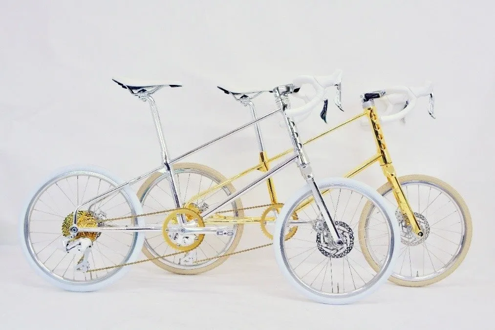 3台の自転車が並んで写っている写真。自転車は、銀色と金色で、白いタイヤとサドル、ハンドルが付いている。背景は白。