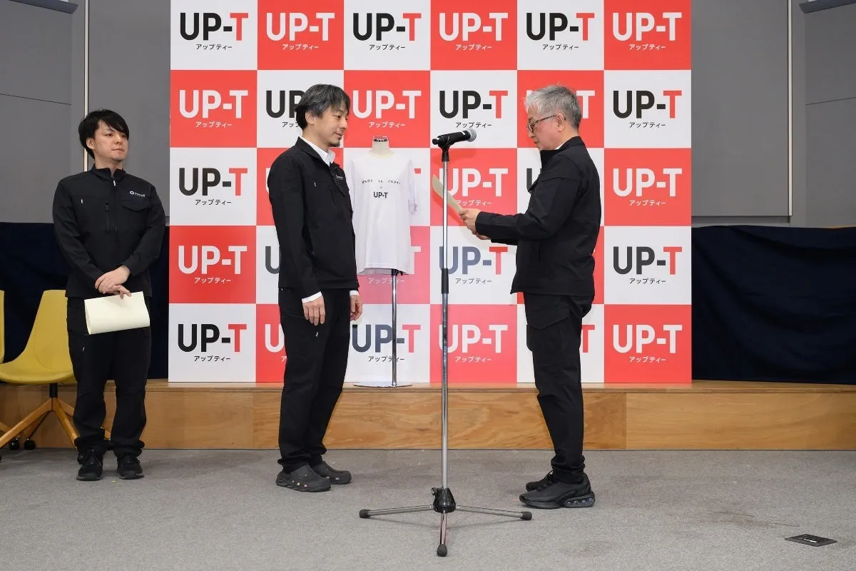 プレゼンテーションをするひろゆき氏とUP-Tのロゴ