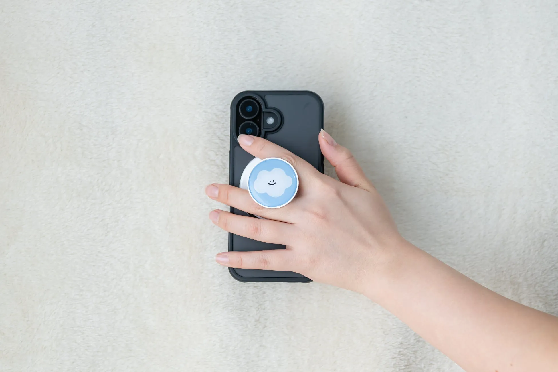 スマホを持った手の写真。スマホには雲の形をしたスマホグリップが付いている。