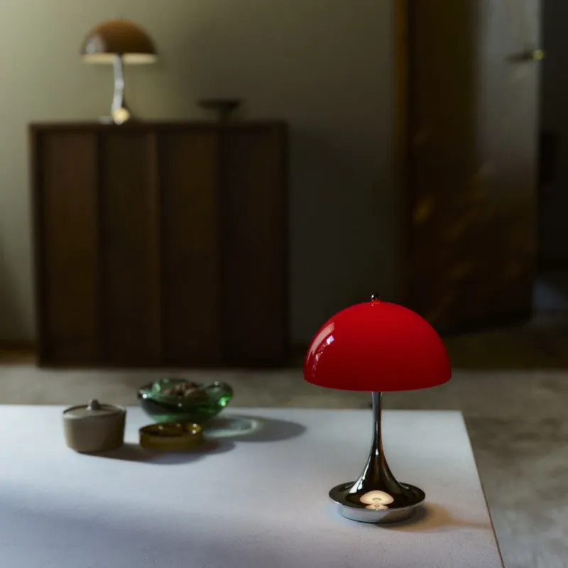 白いテーブルの上に赤いランプが置かれ、その奥には茶色のランプと木製のキャビネットが見える