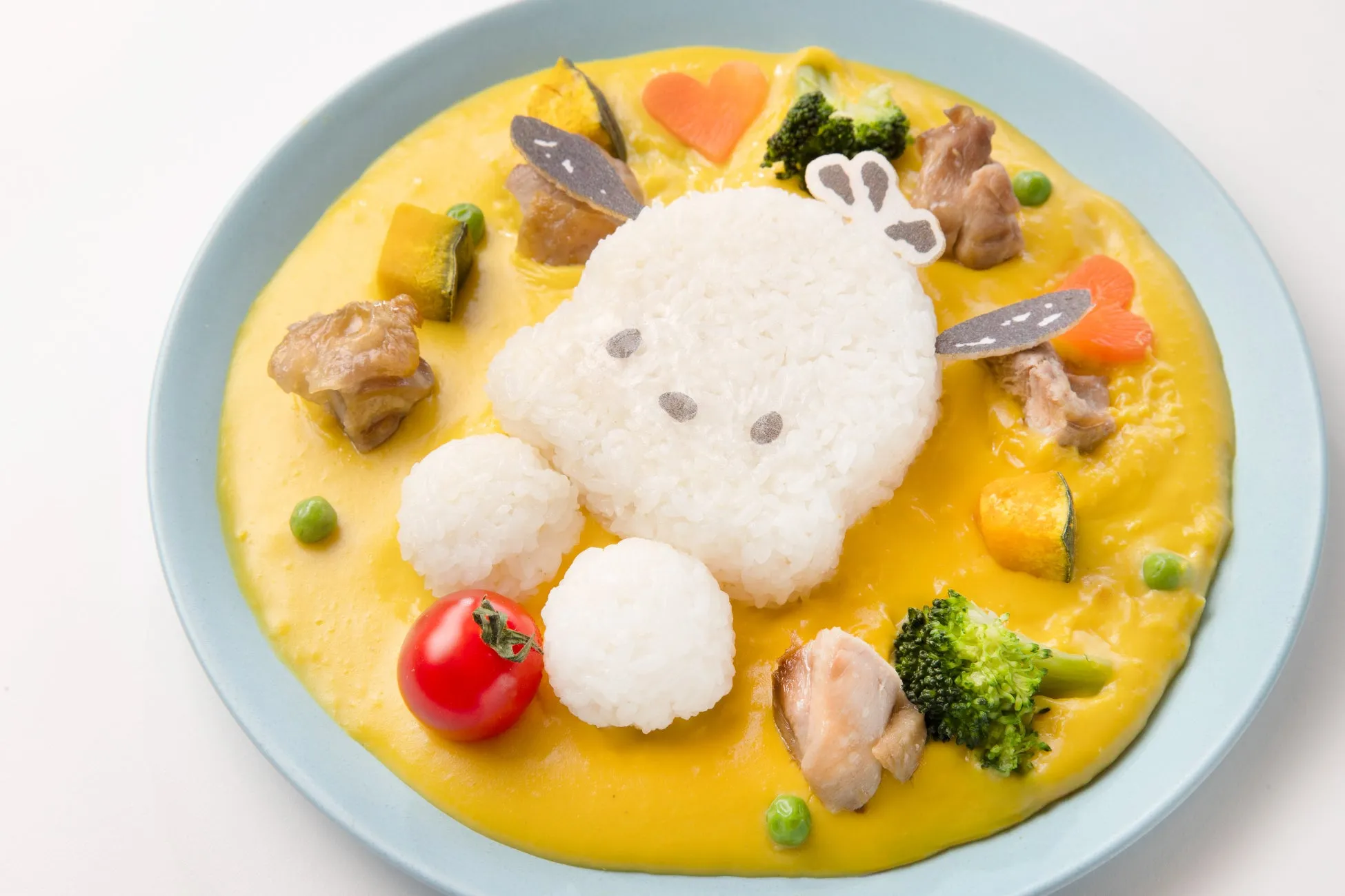 カレーライスの上に、白いご飯でできたキャラクターが乗った可愛らしい料理の写真です。周りには野菜や肉が添えられています。