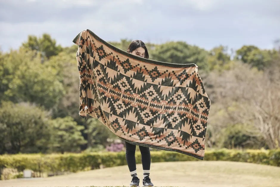 女性がノルディック柄の電気毛布を広げている様子