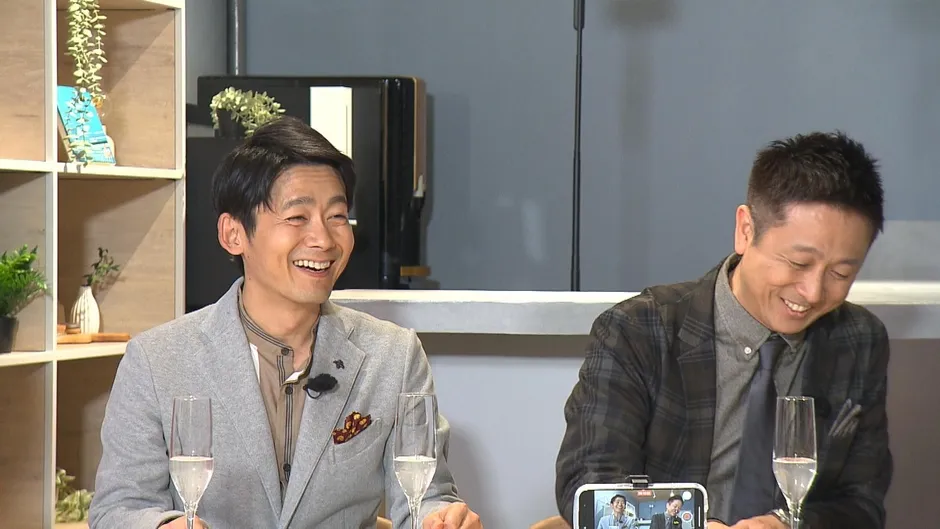 2人の男性がグラスを持ち、笑顔で話をしている様子