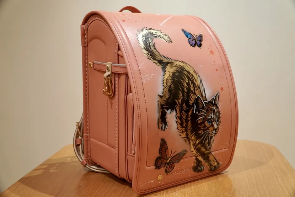 ピンク色のランドセルに猫と蝶のアートカバー