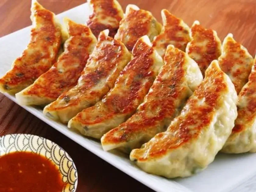 焼き餃子が白皿に並べられ、タレも添えられた写真です。