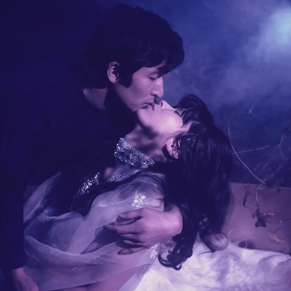 男性が女性にキスをしているロマンチックなシーン。女性は男性に抱きしめられ、光のある場所で横たわっている。