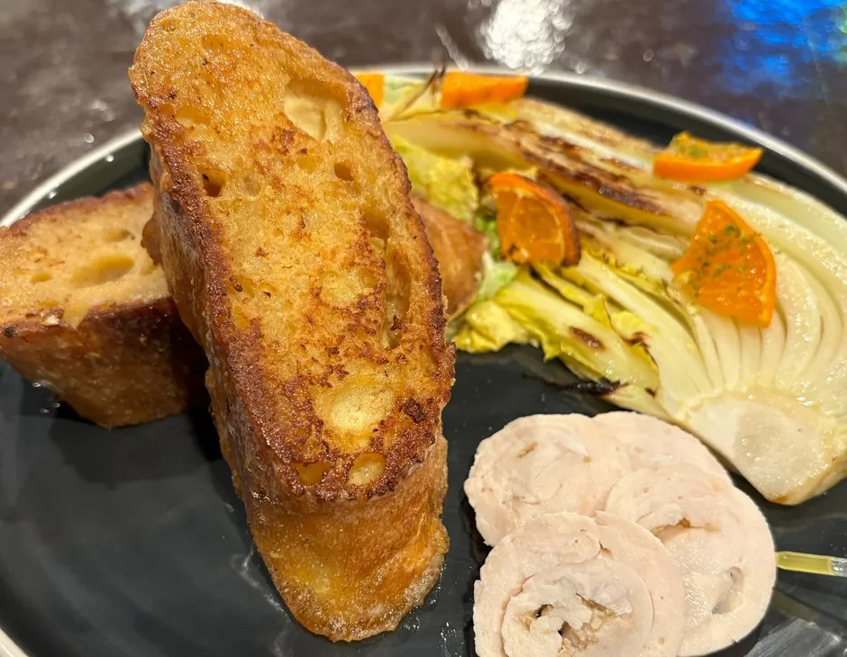 フレンチトースト、オレンジ、鶏肉のスライス、焼いた野菜が盛られたお皿