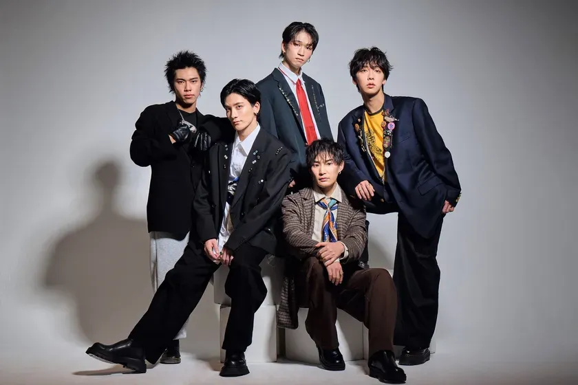 5人の男性がポーズをとっている写真。全員がスーツを着ており、カメラ目線で立っている。