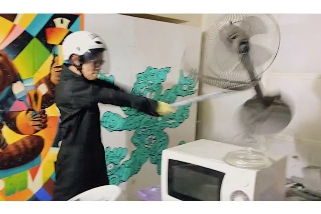 ヘルメットを被った人が扇風機を破壊している