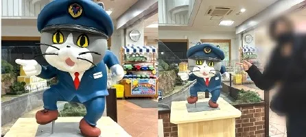 駅長猫の像を指差す人物