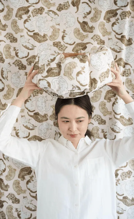 女性が猫柄のバッグを頭に乗せている