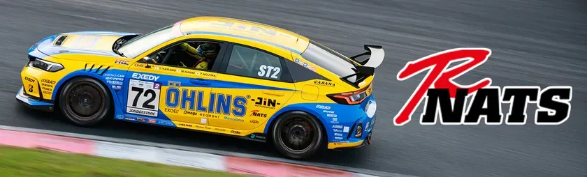 レース中の黄色と青のレーシングカー。車体にはスポンサーロゴと「72」のゼッケンが描かれています。NATSのロゴも確認できます。