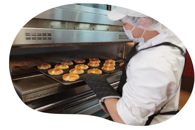 オーブンからパンを取り出すパン職人